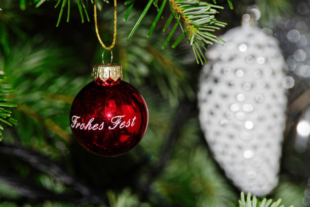 Red Christmas ball with Happy Holiday text in German against blurred Christmas decoration