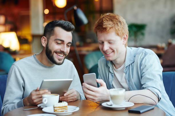 istock Two happy guys with mobile gadgets watching curious stuff in smartphone 1186374153
