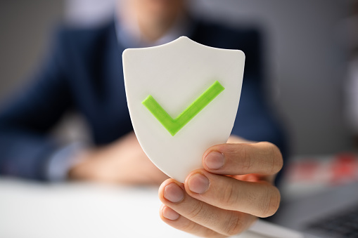 Close-up Of A Businessperson's Hand Holding Shield Shield With Checkmark Icon