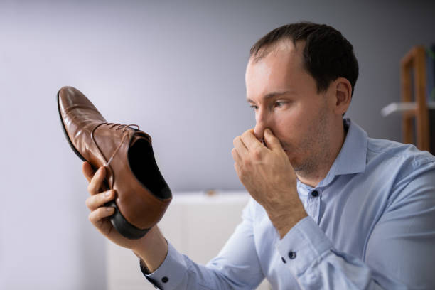 istock Man Covering His Nose While Holding Stinky Shoe 1186375214