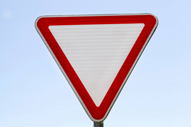 Traffic sign warning for a double curve, and red car in a road, near a gren field. Warning concept.