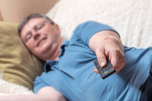 istock Male hand with a TV remote control close-up. The man turns on the TV. Soft focus 1186377607