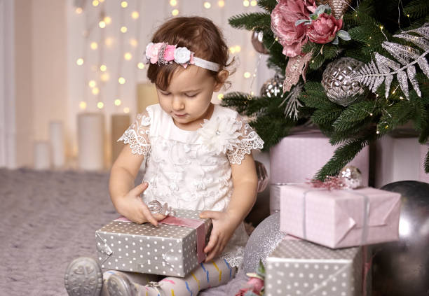 istock Toddler girl looking at Christmas present box 1186378183