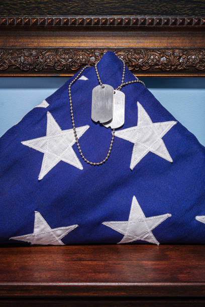 zbliżenie złożonej amerykańskiej flagi z nieśmiertelami siedzącymi na kawałku mantelu w świetle punktowym - american flag folded usa flag zdjęcia i obrazy z banku zdjęć