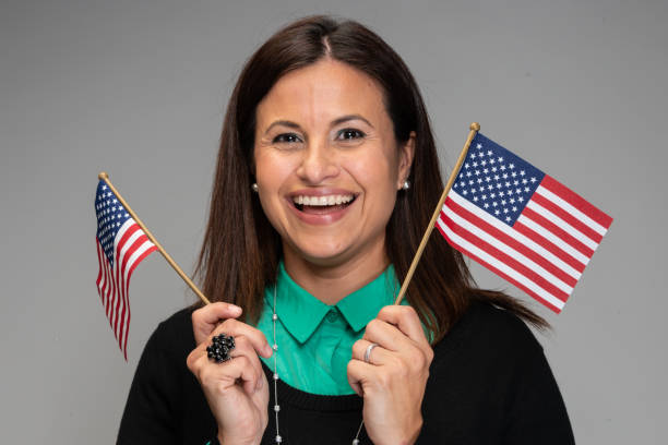 istock Happy hispanic woman posing waving US flags on gray background 1186389290