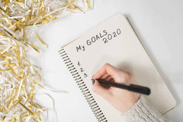 istock Female hands writing My Goals 2020 in a notebook. Tinsel, New Years concept 1186390612