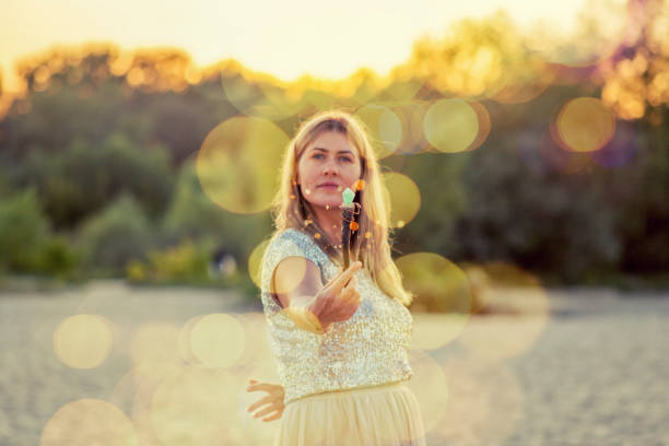 Woman on the beach holds a wand in her hand
