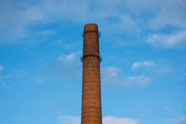 an old factory chimney stands against a blue sky with light clouds. no smoke comes from the chimney. background. - couplers imagens e fotografias de stock