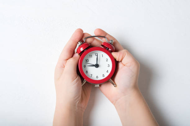 istock Red alarm clock in children's hands on a white background 1186392768