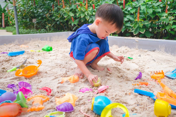 asian 3 - 4 years old toddler boy playing with sand in sandbox at home / school / park, fine motor skills development for little children - sandbox child human hand sand imagens e fotografias de stock