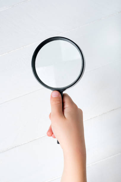 Magnifier in a children's hand on a white background. Close-up Magnifier in a children's hand on a white background. Close-up. babyproof stock pictures, royalty-free photos & images