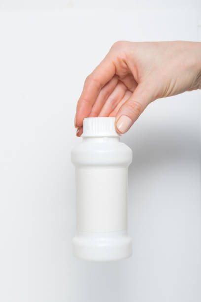 istock White plastic medicine bottle in a female hand. White background 1186396440