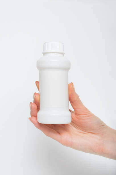 istock White plastic medicine bottle in a female hand. White background 1186396441