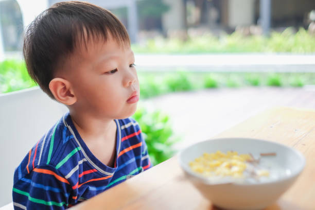 asiático 3 - 4 anos de idade criança menino criança vestindo camisa listrada se recusam a comer alimentos - cereais de pequeno almoço - fotografias e filmes do acervo