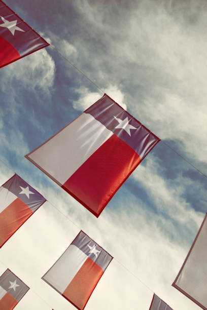 flagi teksasu przed błękitnym niebem i białymi chmurami - texas state flag zdjęcia i obrazy z banku zdjęć