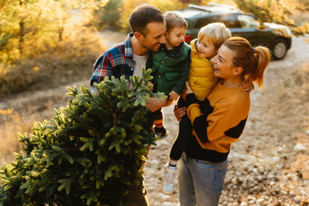 istock Young family carrying home their Christmas tree 1186404425