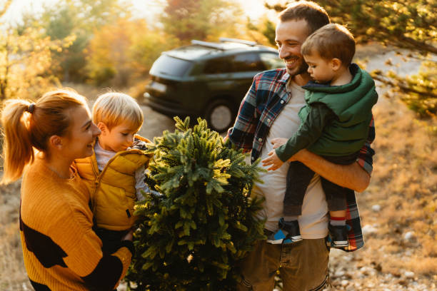 istock Young family carrying home their Christmas tree 1186404430