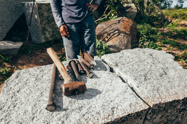 istock Granite extraction for paving cobblestones. Worker and his tools. 1186406039