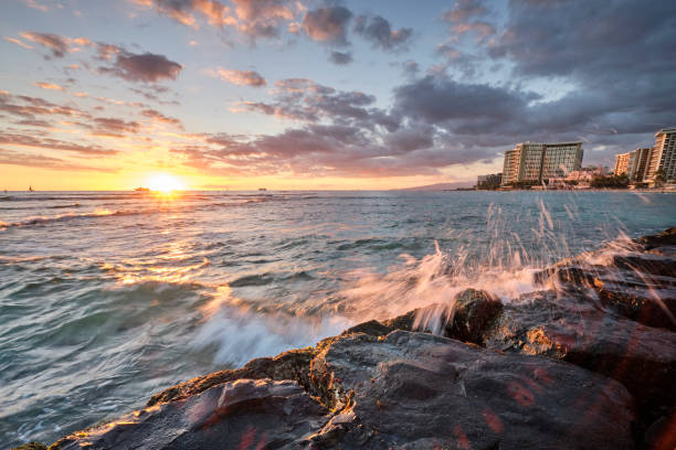 istock Sunset at Waikiki Beach, Hawaii with waves crashing again rocks 1186406239