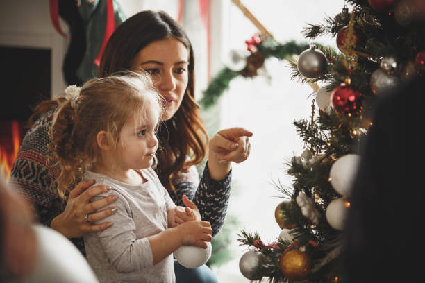 istock Mother and daughter decorating Christmas tree together 1186414482