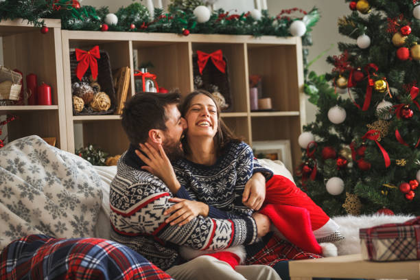 istock Young couple hugging on sofa and enjoying Christmas time together 1186414559