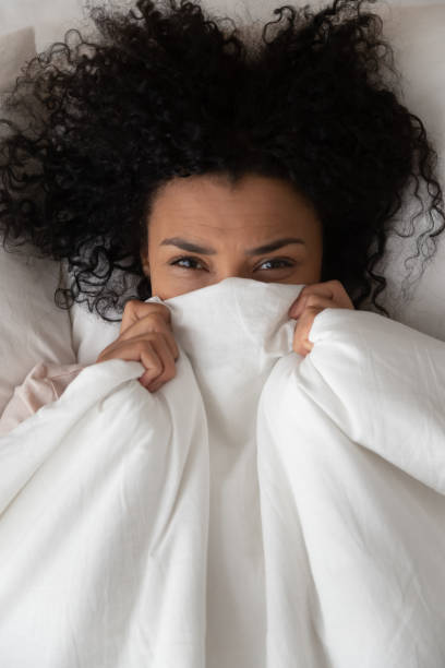 istock Vertical top view woman hides behind blanket looking at camera 1186418411