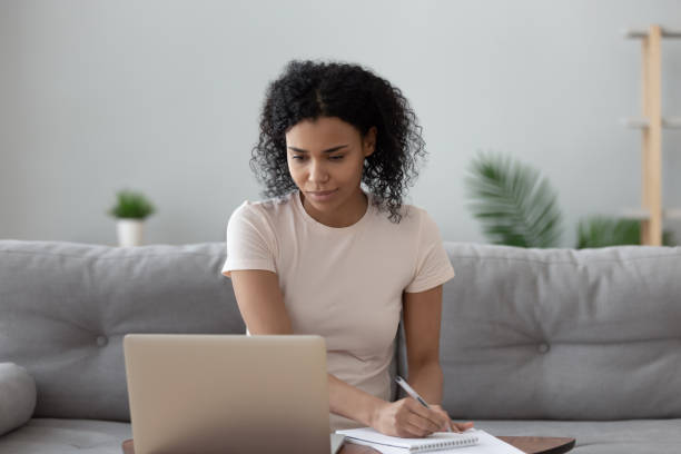 istock African woman looks at computer noting working doing remote job 1186418449