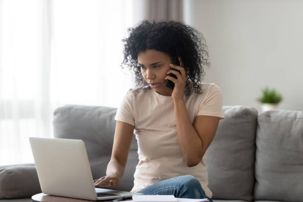 African woman talking on phone looking at computer screen
