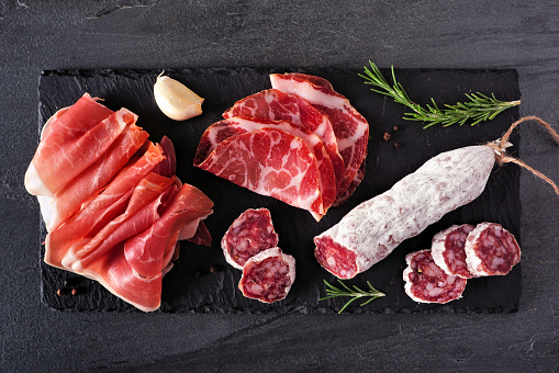 Meat appetizer platter with sausage, and Italian cold cuts. Above view on a slate serving board.