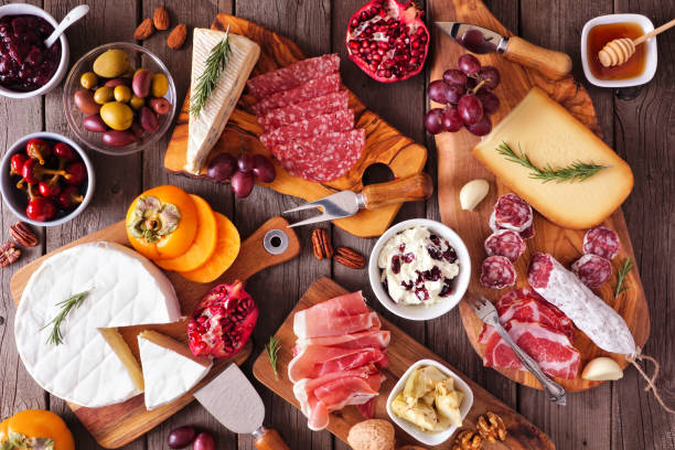 Charcuterie boards of assorted cheeses, meats and appetizers, above view table scene on rustic wood Charcuterie boards of assorted cheeses, meats and appetizers. Above view table scene on a rustic wood background. appetizer plate stock pictures, royalty-free photos & images