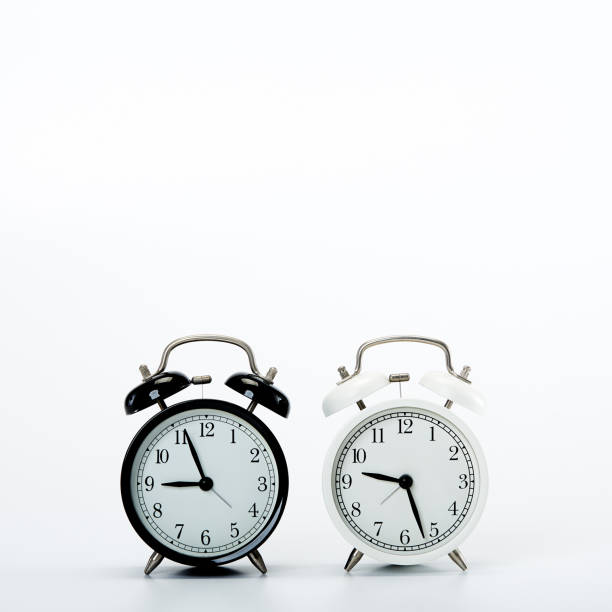 istock Black vintage alarm clock and White clock on white background 1186423780
