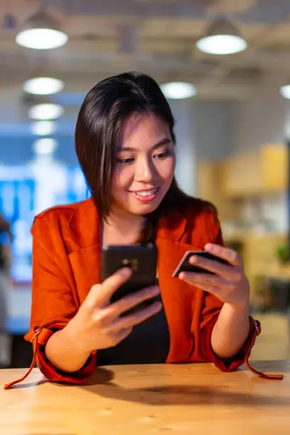 Photo of Young Asian Millennial making purchase using mobile phone.