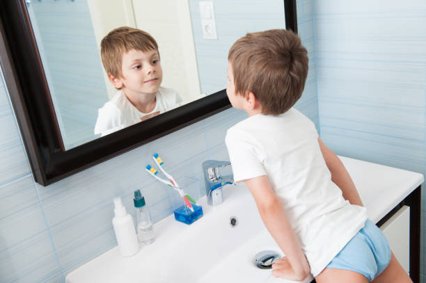 istock handsome healthy small boy watching at his reflection in mirror in bathroom 1186450734