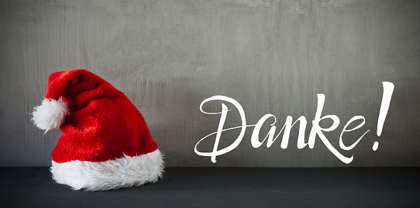 German Calligraphy Danke Means Thank You. Red Santa Claus Hat. Grungy Concrete Background