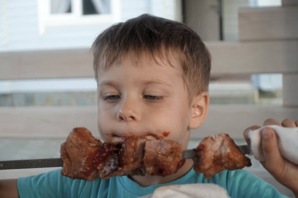 istock Hungry child eating pork neck kebab 1186454301