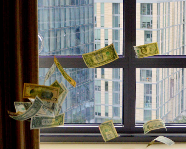 американские долларовые купюры падают на небоскребы - деньги окно стоковые фото и изображения