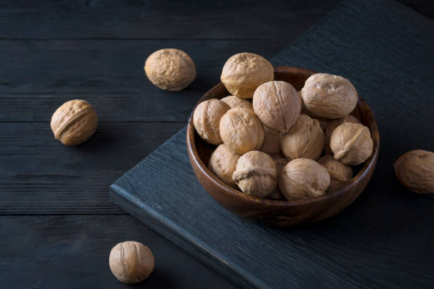 istock Walnuts lie in a wooden bowl on a dark wooden rustic table. 1186463577
