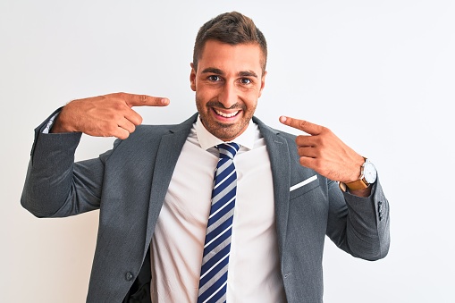 Young handsome business man wearing suit and tie over isolated background smiling cheerful showing and pointing with fingers teeth and mouth. Dental health concept.