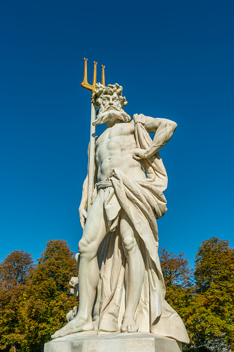 Munich, Germany - October 13, 2019: Neptune or Poseidon with trident in the public park of Nymphenburg castle (Schloss Nymphenburg). The palace, together with its park, is one of the most visited sights of Munich.