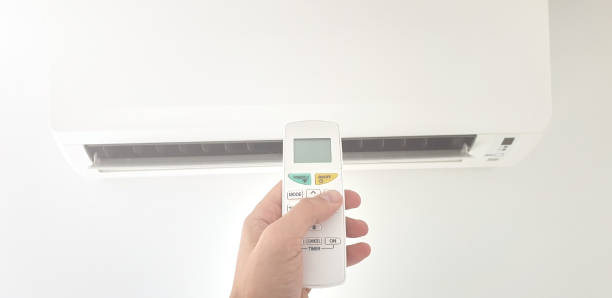 istock Modern air conditioner unit with a hand holding a remote. 1186472244