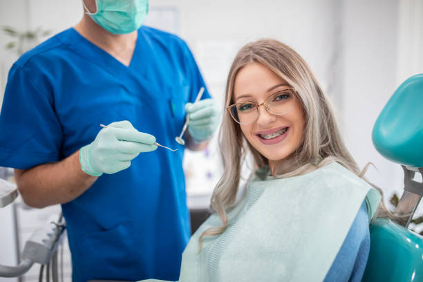 Beautiful young woman with braces having dental treatment at dentist's office stock photo