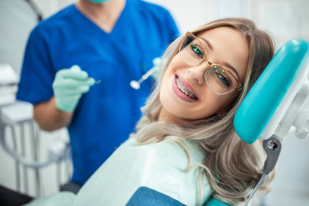 hermosa mujer con aparatos ortopédicos que tienen tratamiento dental en el consultorio del dentista - banda correctora fotografías e imágenes de stock