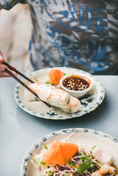istock Man eating rice paper rolls with chopsticks in cafe 1186475798