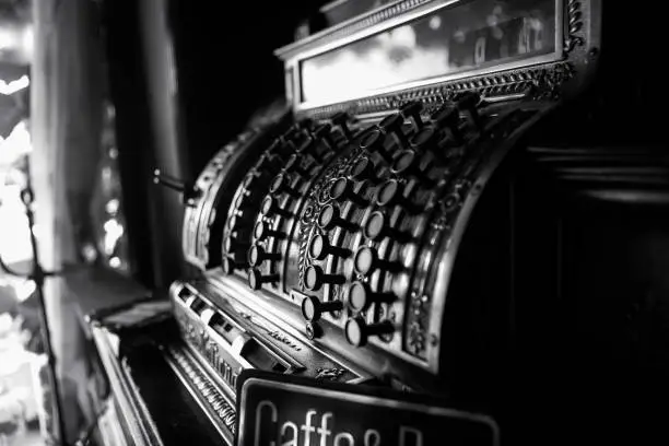 Photo of Black and white image of an old 19th century cash register. Selective focus on cashier buttons.