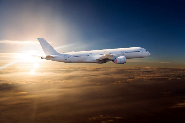 The passenger plane flies over the clouds during sunset