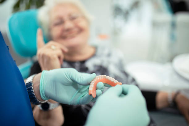 zahnarzt zeigt einem patienten zahnprothesen - künstliches gebiss fotos stock-fotos und bilder