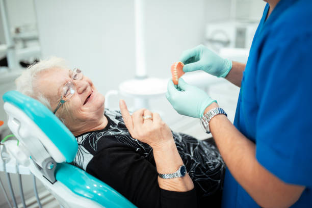 стоматолог показывает зубные протезы старшему пациенту - dentists chair people care medical equipment стоковые фото и изображения