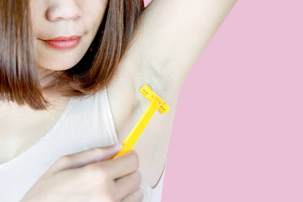 istock Asian woman using razor shaving hair under armpit isolated on pink background 1186483322