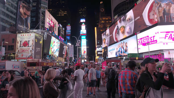 мигающие объявления и красочные рекламные щиты вдоль тротуара на таймс-сквер - times square flash стоковые фото и изображения