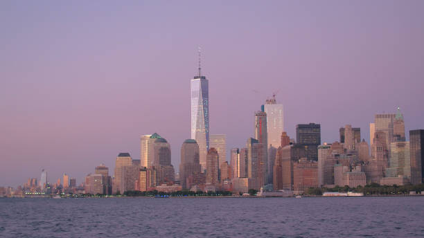 resplandor del amanecer púrpura en los rascacielos en el icónico horizonte del centro de manhattan - manhattan dusk new york state sunrise fotografías e imágenes de stock